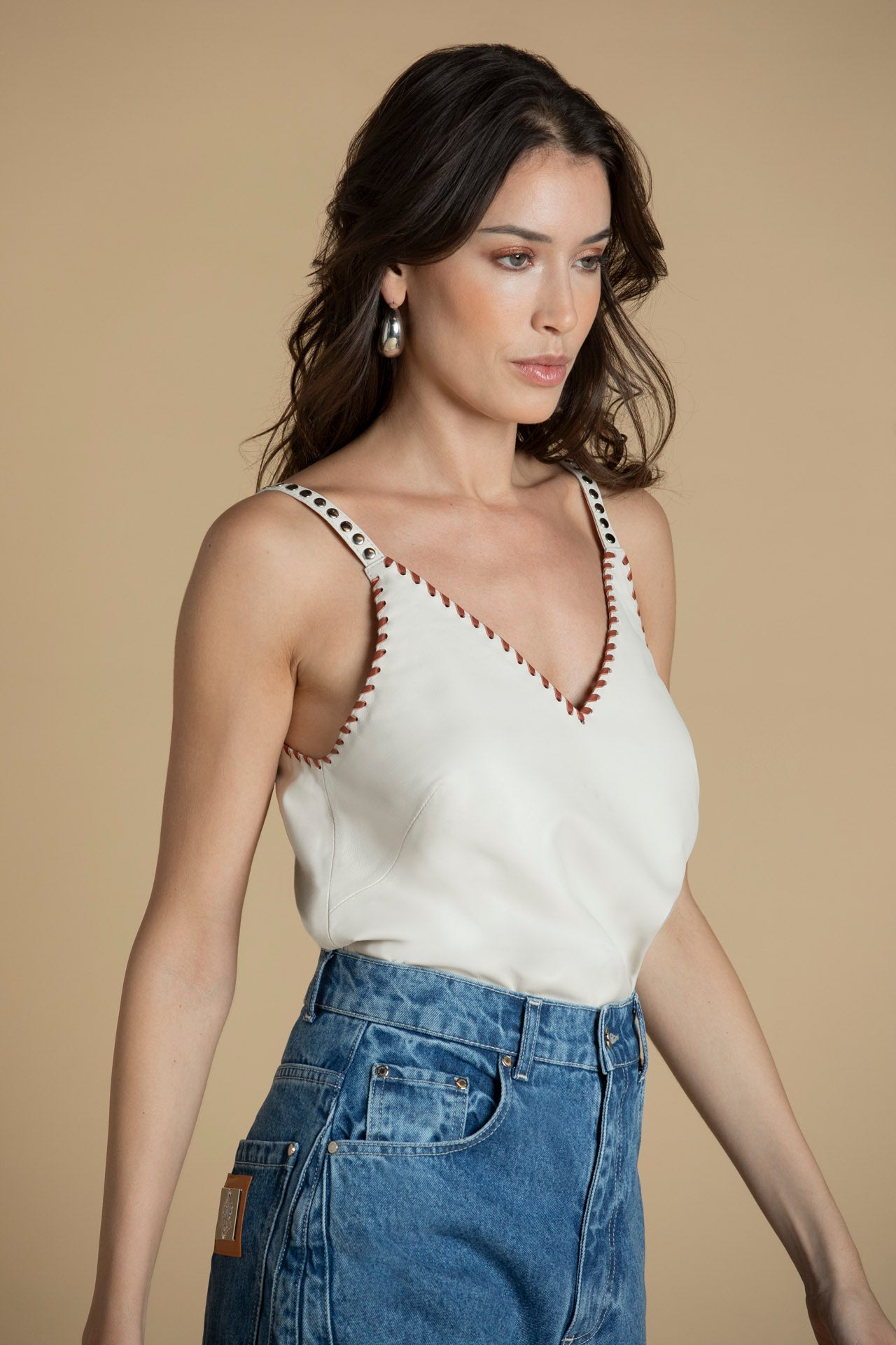 Pormenor do entrançado castanho e das tachas metálicas no top de pele SH x GM