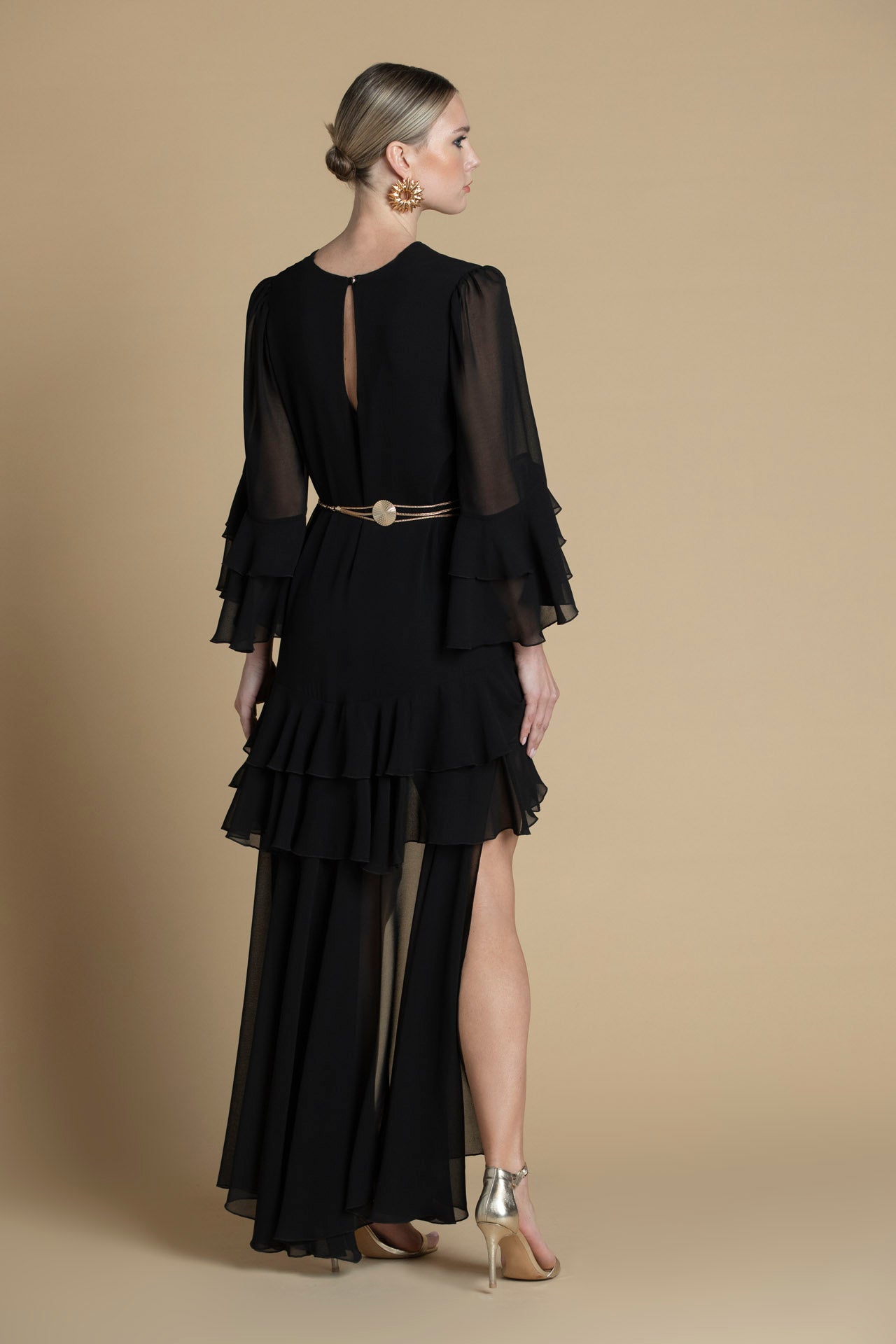 costas do vestido preto com mangas fluidas e corte assimétrico